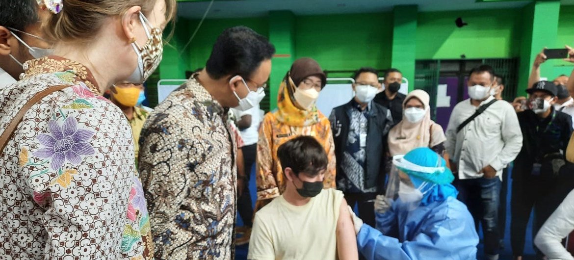 The Governor of DKI Jakarta together with UNHCR Indonesia Representative and members of KADIN (Indonesia Chambers of Commerce and Industry) observe a young refugee being vaccinated.