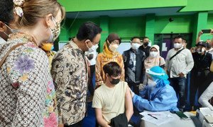The Governor of DKI Jakarta together with UNHCR Indonesia Representative and members of KADIN (Indonesia Chambers of Commerce and Industry) observe a young refugee being vaccinated.