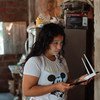 इक्वेडोर के मॉण्टे सिनाई में, एक किशोरी अपने गर पर, ऑनलाइन शिक्षा प्राप्ति के लिये तैयारी करते हुए.
