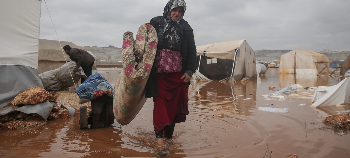 A woman tries to rescue her belongings after floods inundated her camp in north-west Syria in January 2021.