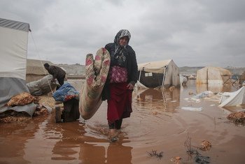 A woman tries to rescue her belongings after floods inundated her camp in north-west Syria in January 2021.