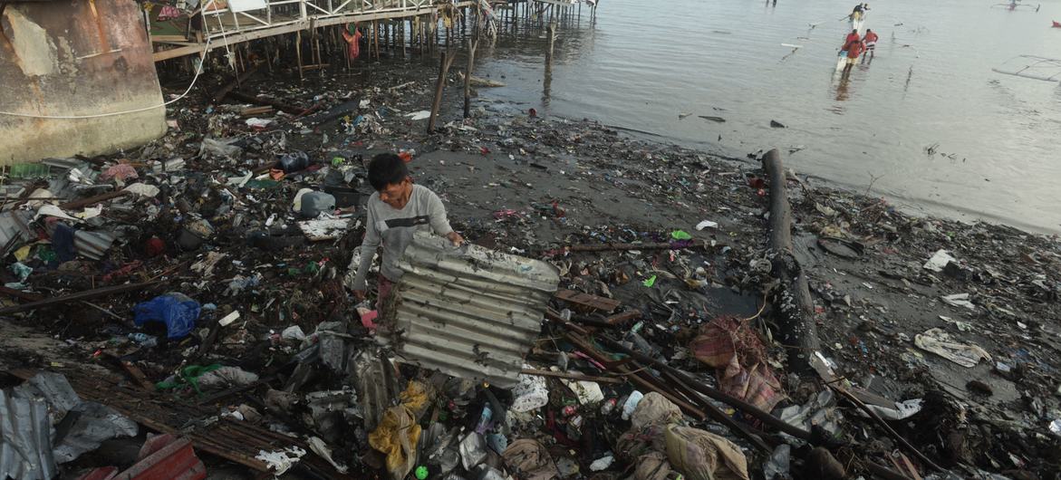 Un homme récupère une tôle sur une plage ravagée par le typhon Rai, aux Philippines.