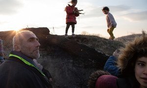 A Syrian family prepares to huddle down by a fire out of the wind while children gather branches to burn, as they deliberate how to get home after a failed crossing attempt at the Edirne border with Greece.