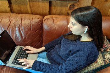 Young woman wears earbuds while working on her laptop.