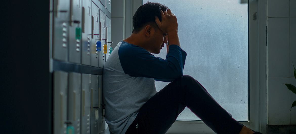 A thoughtful young man, sitting in a changing room.