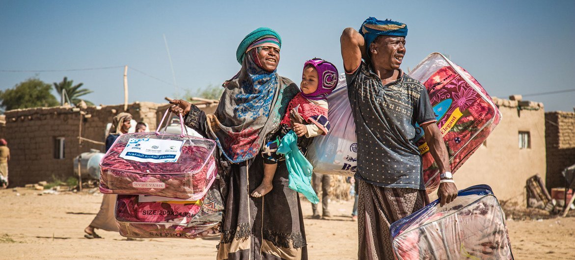 Familia desplazada en Marib, Yemen, se dirige a un albergue luego de recibir un paquete de ayuda para el invierno.