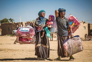A displaced family in Marib, Yemen, carries a winter aid package back to their shelter.