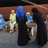 من الأرشيف: امرأتان تطلبان الماء من موظف في اليونيسف في ميناء طرابلس، عاصمة ليبيا.