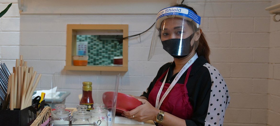 A woman follows health protocols by wearing a face mask at work in a restaurant in Indonesia.