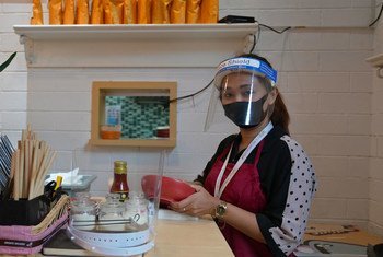 A woman follows health protocols by wearing a face mask at work in a restaurant in Indonesia.