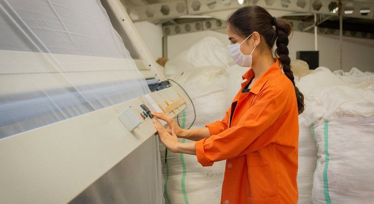 Une femme porte un masque facial lorsqu'elle travaille dans une entreprise textile à İzmir, en Turquie.