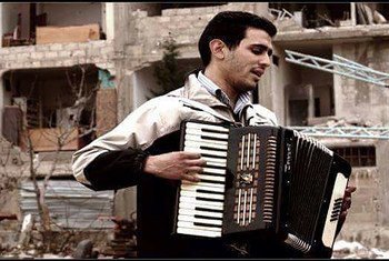 أيهم أحمد وهو يعزف الأوكروديون في مخيم اليرموك