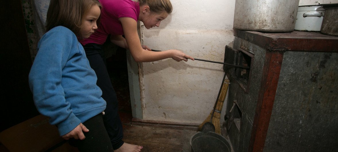In their Olenivka settlement house in the non-government controlled area of Donetsk region, 11-year old Alika and her six-year old sister Sofia add coal to the stove.