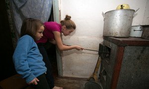 Alika, de 11 años, y Sofía, de 6, echan carbón a la estufa en su casa de Olenivka, en la región de Donetsk, Ucrania.