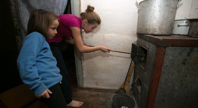 Alika, de 11 años, y Sofía, de 6, echan carbón a la estufa en su casa de Olenivka, en la región de Donetsk, Ucrania.