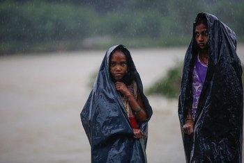 尼泊尔南部与印度接壤的普塔里地区，两名女童用塑料布遮挡如注的暴雨。