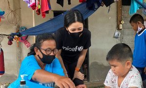 UNICEF volunteer, Rasa Pattikasemkul (centre), interacts with a young boy in a rare face-to-face meeting during the COVID-19 lockdown.