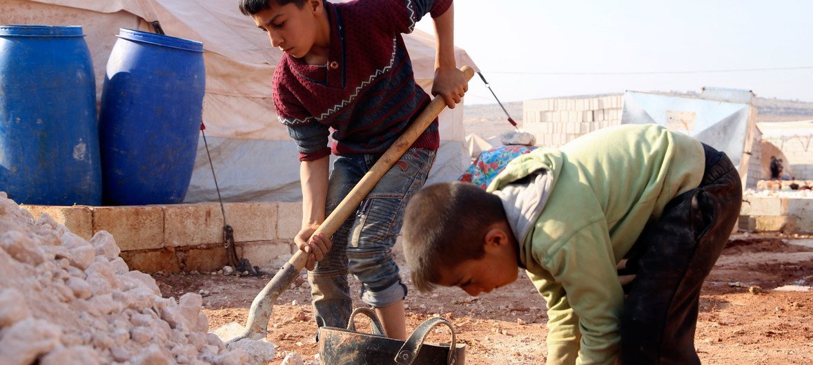 أطفال يساعدون أسرهم النازحة في محافظة إدلب في بناء ملاجئ للحماية من البرد بمستوطنة غير رسمية في كيلي، بالقرب من الحدود مع تركيا.