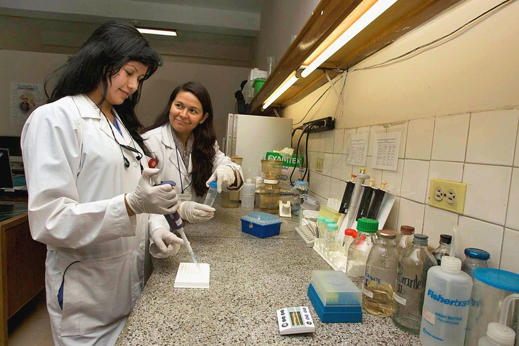 在哥伦比亚国家癌症研究所，一名研究助理（左）正在接受一位生物学家的培训。