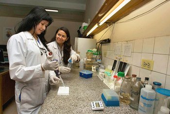 A research assistant (left) receives training from a biologist at the National Cancer Institute of Columbia.