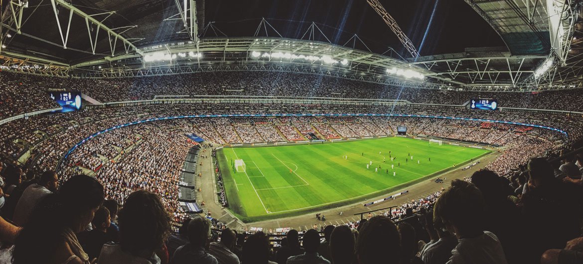 A crowd watching a football game inside Wembley Stadium in England.