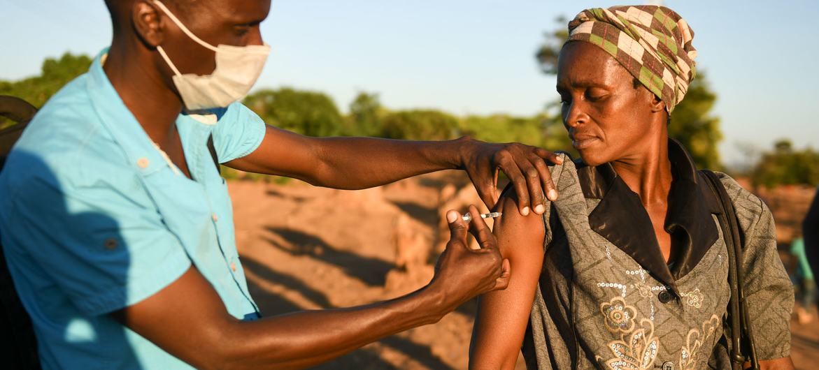 马拉维的一名卫生工作者给一名妇女接种新冠疫苗。
