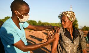 马拉维的一名卫生工作者给一名妇女接种新冠疫苗。