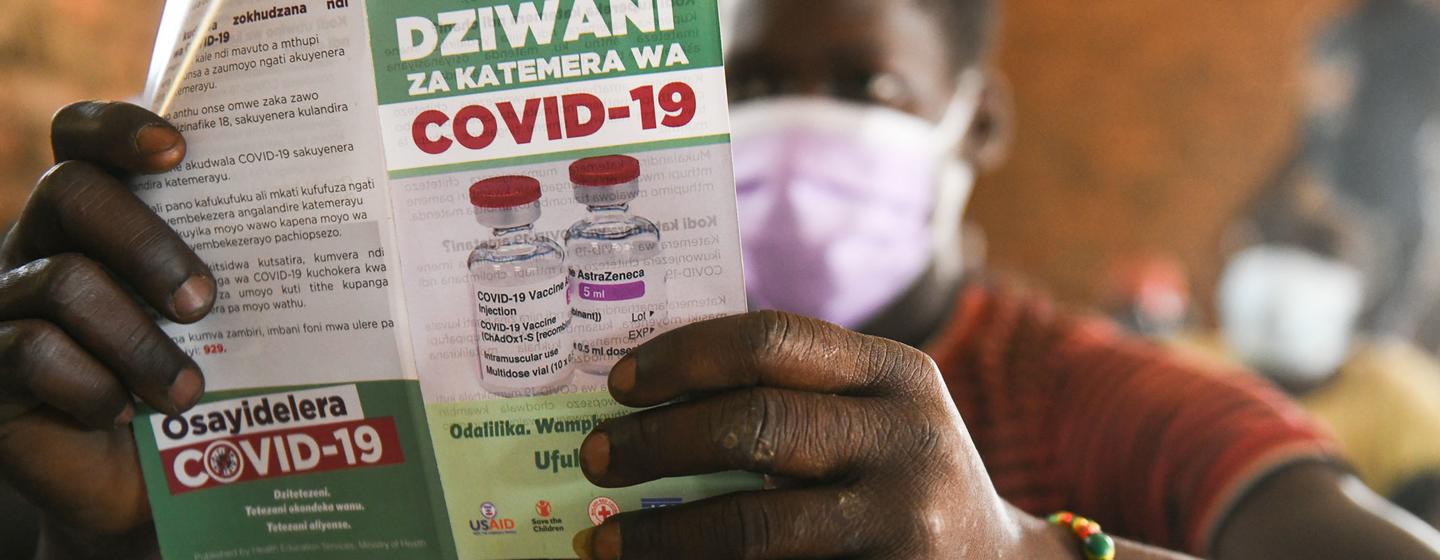 Un homme lit une brochure d'information sur le vaccin Covid 19 avant de recevoir sa première dose, au Malawi.