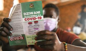 在马拉维，一名男子在接受第一剂疫苗之前阅读有关新冠疫苗的信息手册。