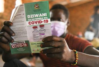 Homem lê folheto sobre vacinação da Covid-19 no Malauí. 