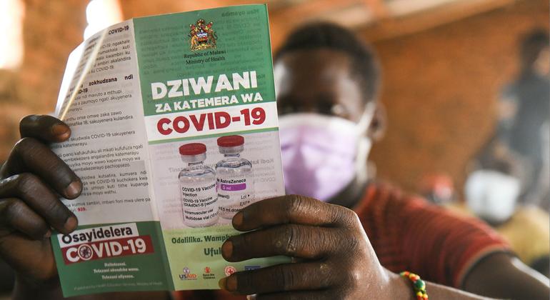 Homem lê folheto sobre vacinação da Covid-19 no Malauí. 