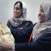 من اليمين: الدكتورة أفراح ثابت الأديمي، أخصائية برامج الصحة الإنجابية بمكتب صندوق الأمم المتحدة للسكان في اليمن، تحمل طفلا حديث الولادة في مستشفي في اليمن.