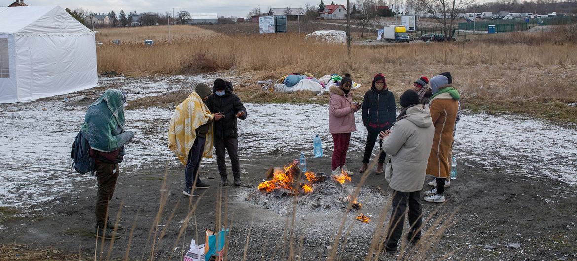 Refugiados da Ucrânia se aquecem em fogueira após cruzarem a fronteira para a Polônia em Medyka