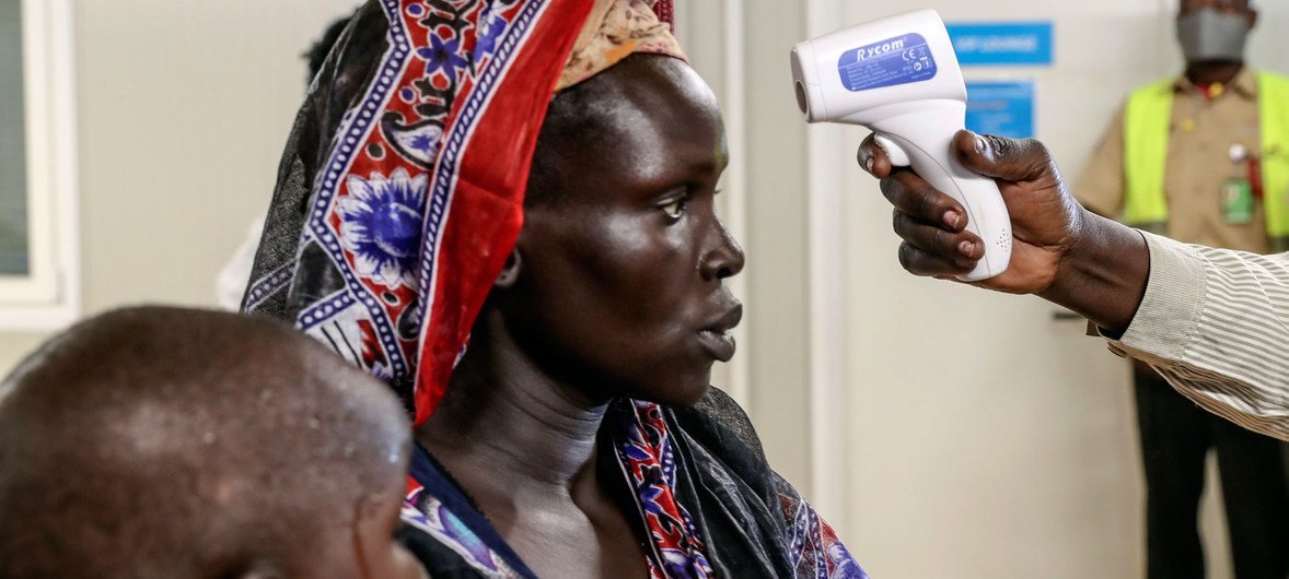 An internally displaced woman voluntarily returning to her home in Bentiu, South Sudan, is being checked for fever. 