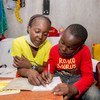 Un garçon de dix ans étudie avec l'aide de sa mère à la maison dans le quartier informel de Mathare à Nairobi, au Kenya.