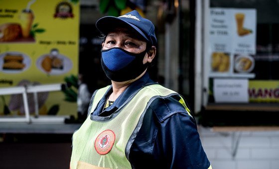 عاملة نظافة عام ترتدي قناع وجه فيما تعمل أثناء جائحة كوفيد-19في تايلند.