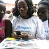 Adolescent girls in Liberia read information a mobile phone in the West Point neighbourhood of Monrovia, the capital. 