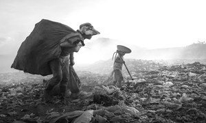 A child works alongside his mother picking through rubbish at a dump in Viet Nam. 