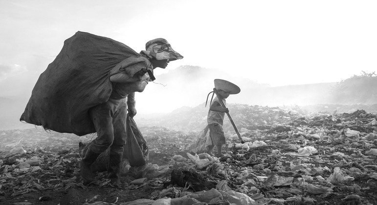 A child works alongside his mother picking through rubbish at a dump in Viet Nam. 