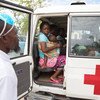 A mother and her baby sit in an ambulance at an accommodation centre in Beira, Mozambique, where her 2-year-old daughter is being treated for malaria.