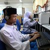 一名十几岁的男孩在马来西亚吉隆坡的一所特殊教育学校使用文字转语音软件来操作计算机。