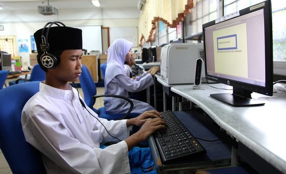 Adolescente usando software para operar computador em escola em Kuala Lumpur