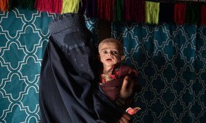 Dans le district de Maiwand, province de Kandahar, une Afghane portant une burqa tient un nourrisson gravement malnutri.