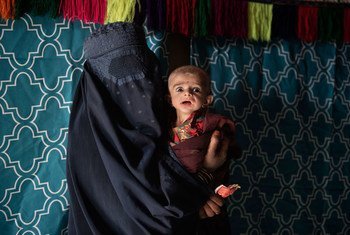 Мать принесла своего сильно истощенного ребенка на осмотр медиков в провинции Кандагар.