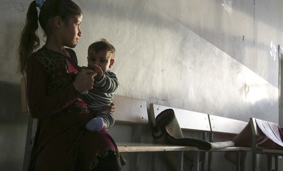 Menina segura bebê em escola que virou abrigo em Ar-Raqqa, na Síria 