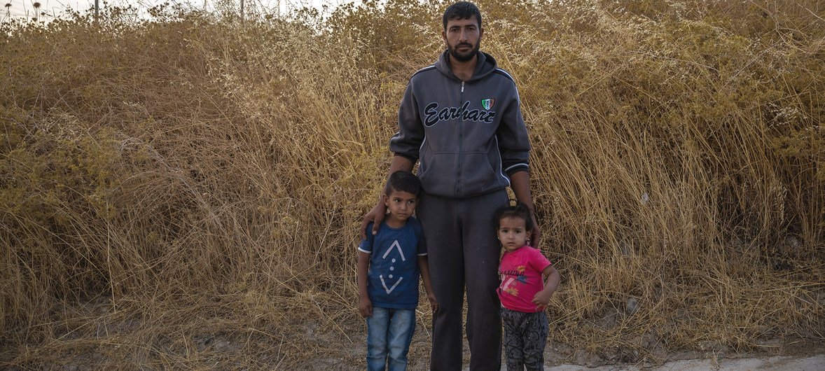 A Syrian father stands with his children at Bardarash camp in Duhok, Iraq, a day after arriving.