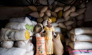 A female farmer stands in front of seed bags stored in a warehouse in a agri-business centre in Sierra Leone.