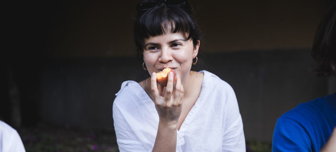 A woman eats a peach in Guatemala.