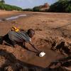 सोमालिया में एक बच्चा, सूखे के कारण सूख चुकी नदी में बचे-खुचे पानी में से कुछ पानी बटोरने की कोशिश करते हुए.