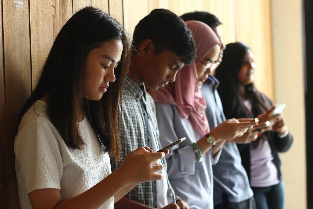 马来西亚的年轻人使用他们的手机保持联系。